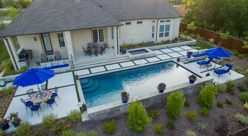 Diseño de piscina con fuente minimalista de tamaño medio rectangular en patio trasero con adoquines de piedra natural