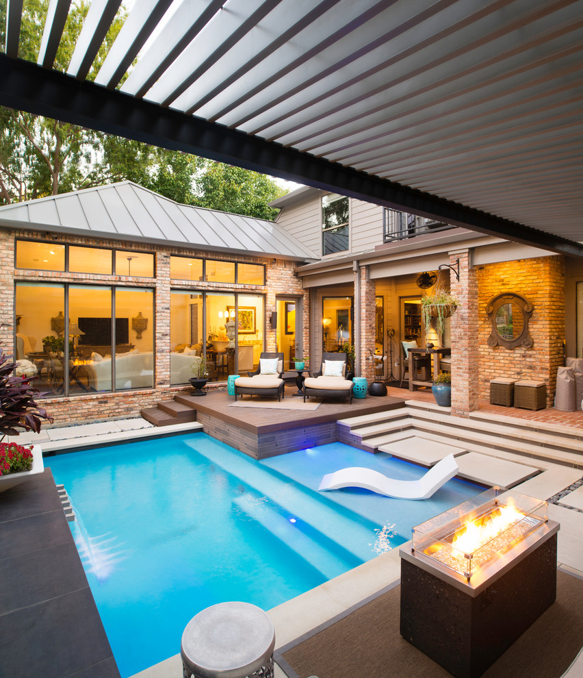 Modern inredning av en liten l-formad pool på baksidan av huset, med naturstensplattor