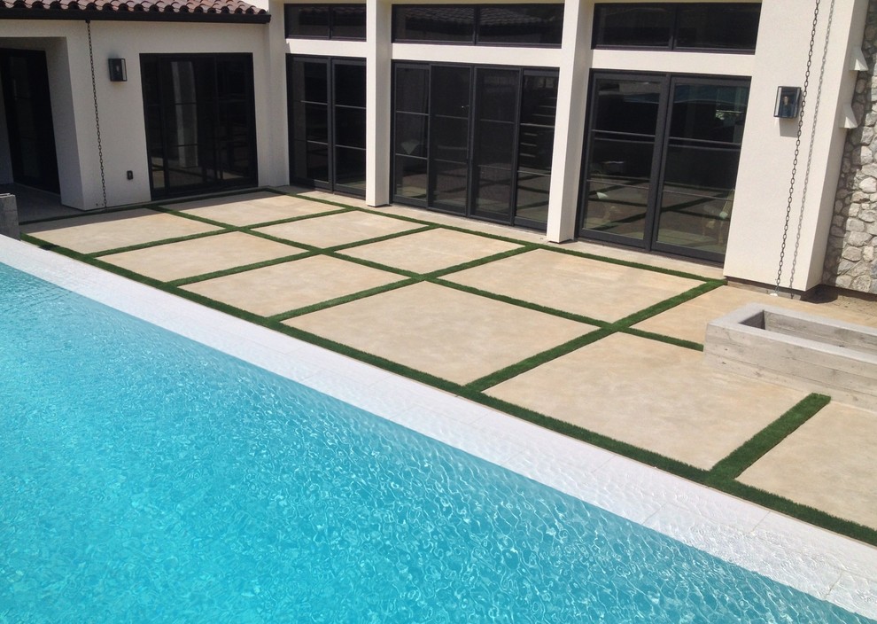 Foto de piscina alargada contemporánea de tamaño medio rectangular en patio trasero con losas de hormigón