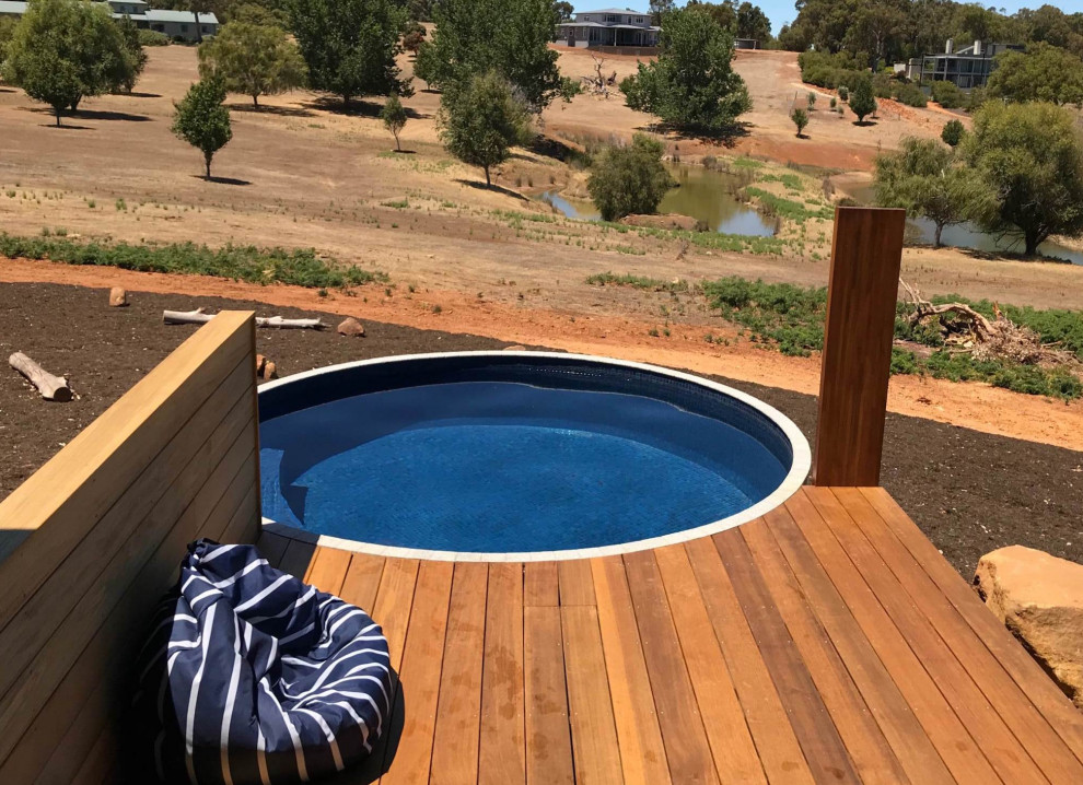 Réalisation d'une petite piscine hors-sol et arrière minimaliste ronde avec une terrasse en bois.