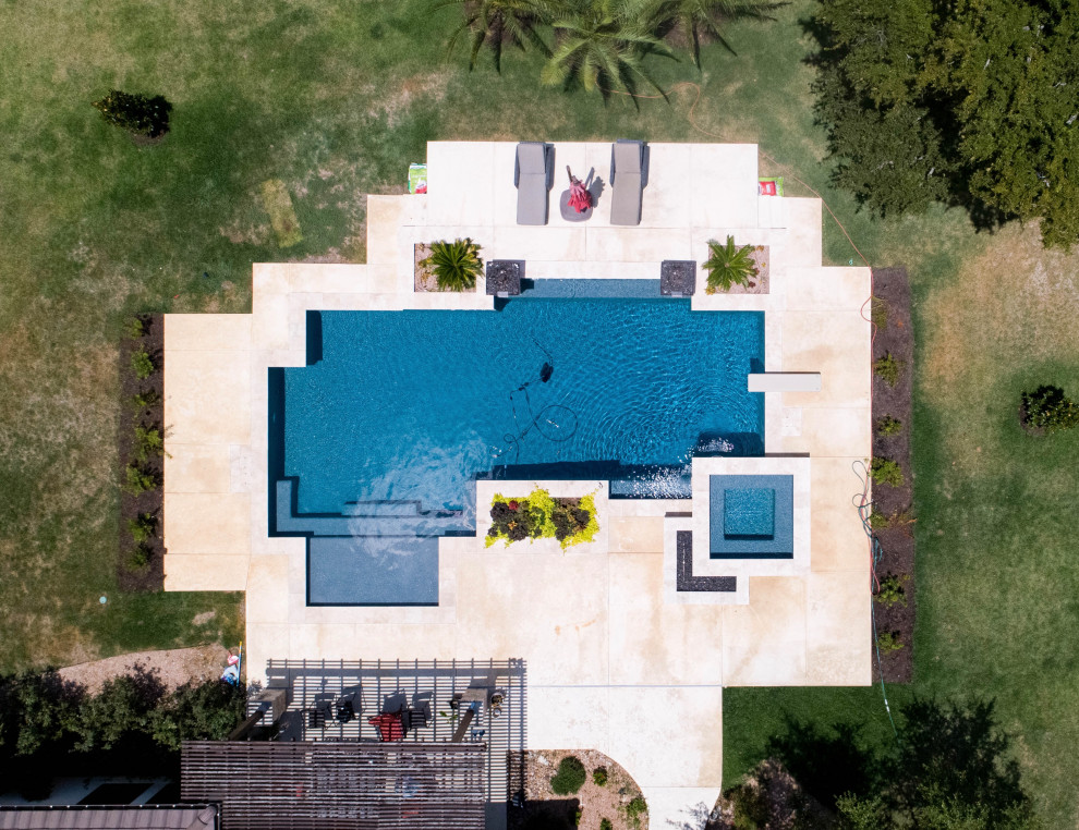Imagen de piscina con fuente contemporánea grande rectangular en patio trasero con losas de hormigón