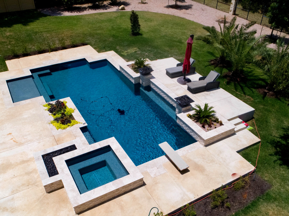 Diseño de piscina con fuente actual grande rectangular en patio trasero con losas de hormigón
