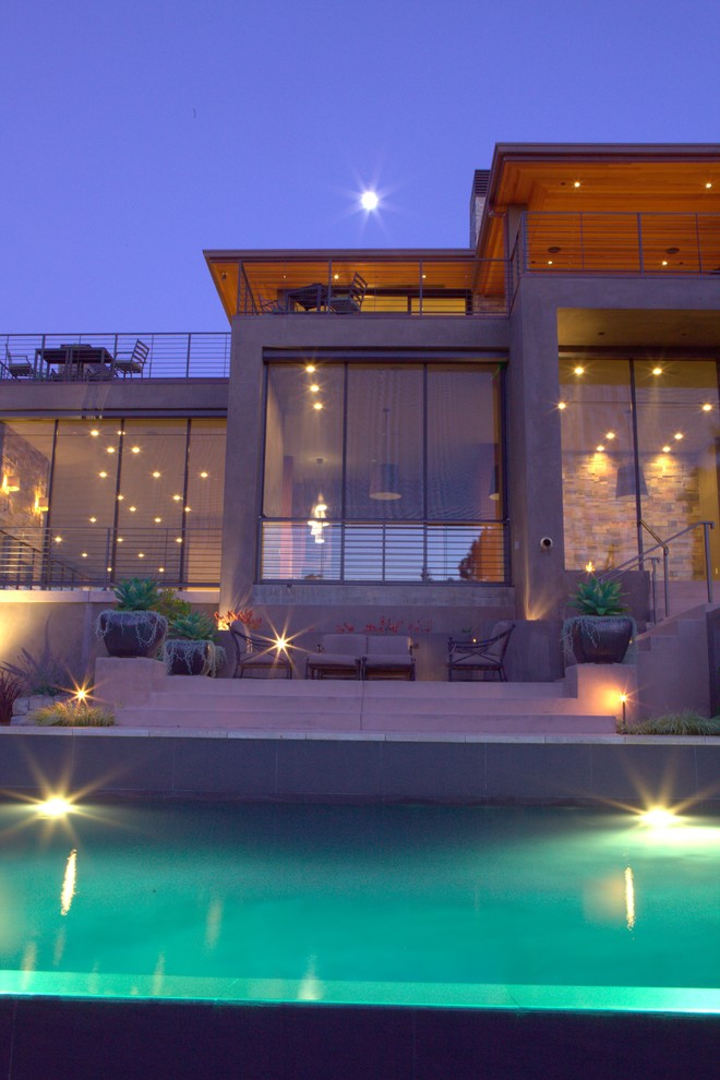 Immagine di una grande piscina a sfioro infinito moderna rettangolare dietro casa con una dépendance a bordo piscina e piastrelle