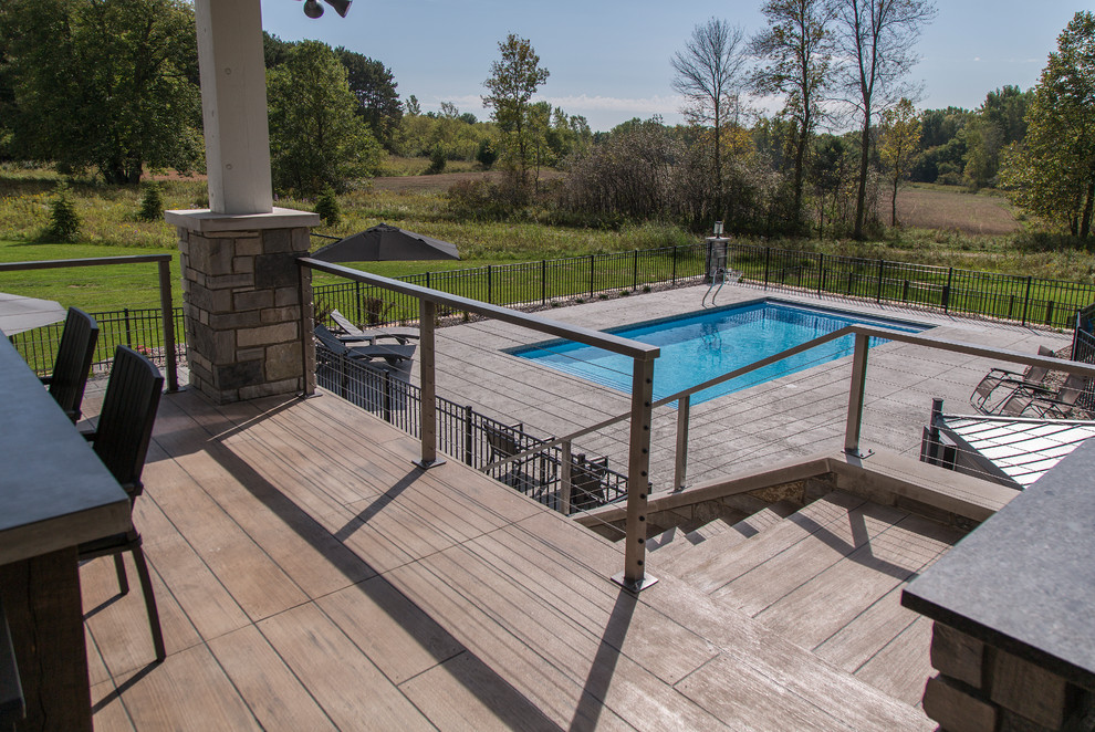 Example of a large trendy backyard rectangular lap pool design in Other with decking