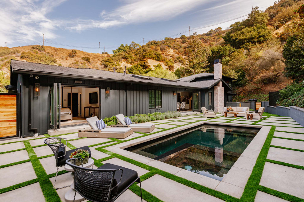 Imagen de piscina natural de estilo de casa de campo rectangular en patio trasero con adoquines de hormigón