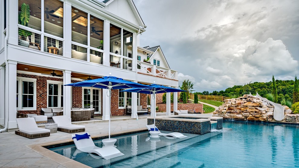 Expansive farmhouse back custom shaped infinity swimming pool in Nashville with a water slide and concrete paving.