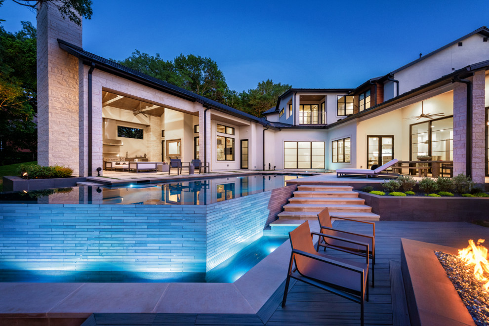 Imagen de piscina infinita de estilo de casa de campo de tamaño medio a medida en patio trasero con paisajismo de piscina y adoquines de hormigón