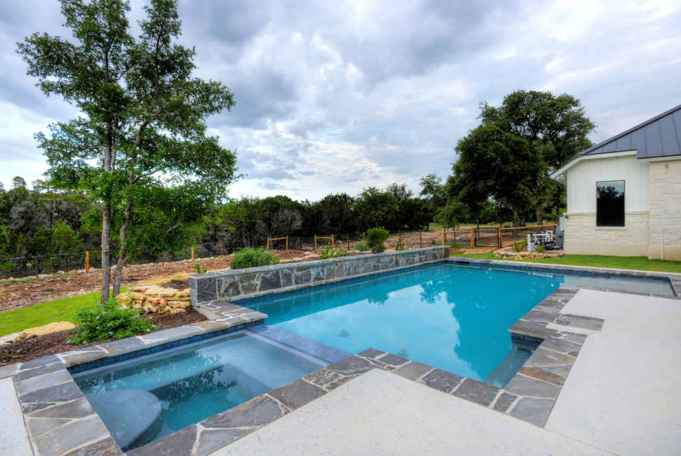 Esempio di una piscina naturale country rettangolare di medie dimensioni e dietro casa con una vasca idromassaggio e lastre di cemento