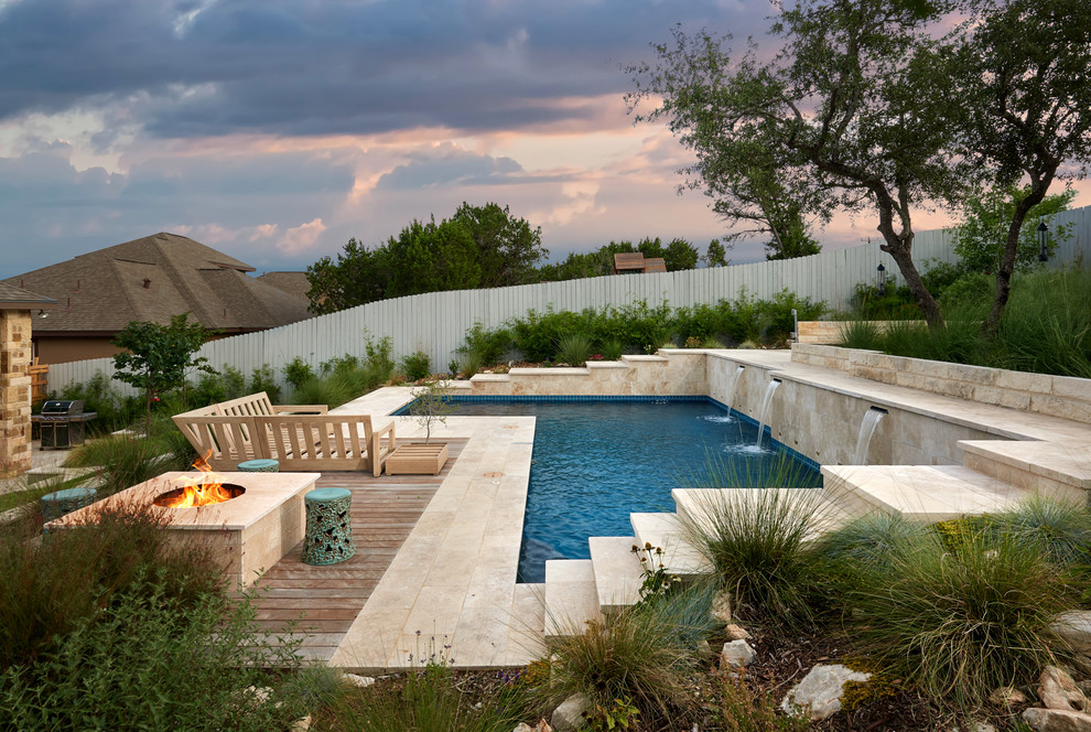 Mittelgroßer Moderner Schwimmteich hinter dem Haus in L-Form mit Natursteinplatten und Wasserspiel in Austin