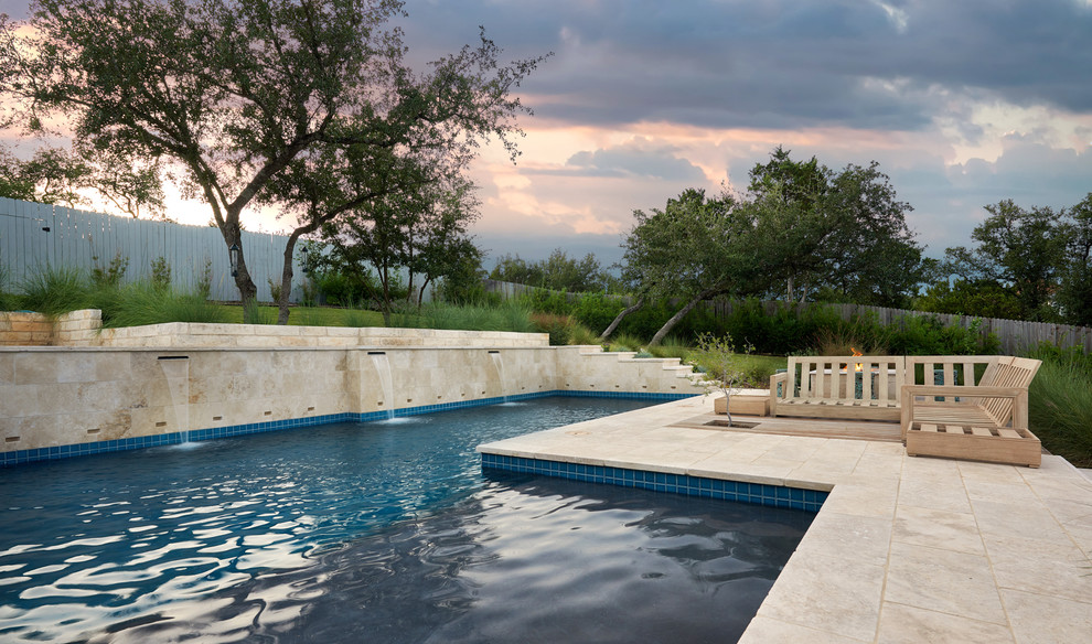 Ejemplo de piscina natural actual de tamaño medio en forma de L en patio trasero con adoquines de piedra natural