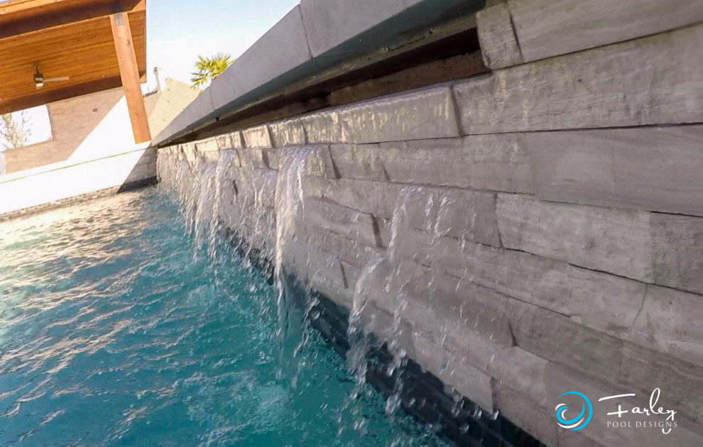 Стильный дизайн: большой бассейн-инфинити произвольной формы на заднем дворе в стиле модернизм с фонтаном и покрытием из декоративного бетона - последний тренд