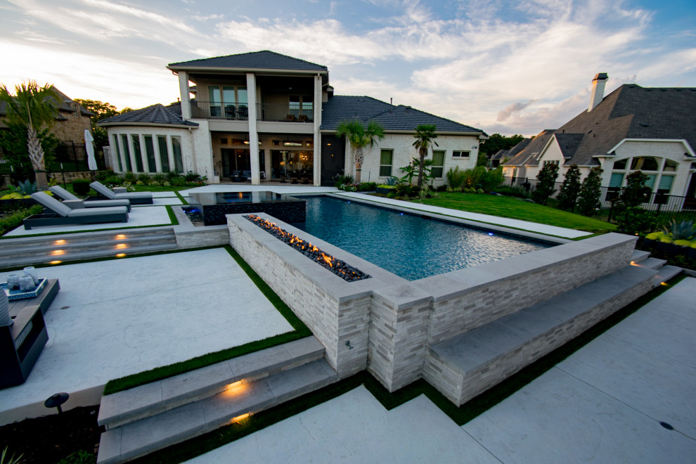 Modelo de piscina con fuente infinita minimalista grande a medida en patio trasero con suelo de hormigón estampado