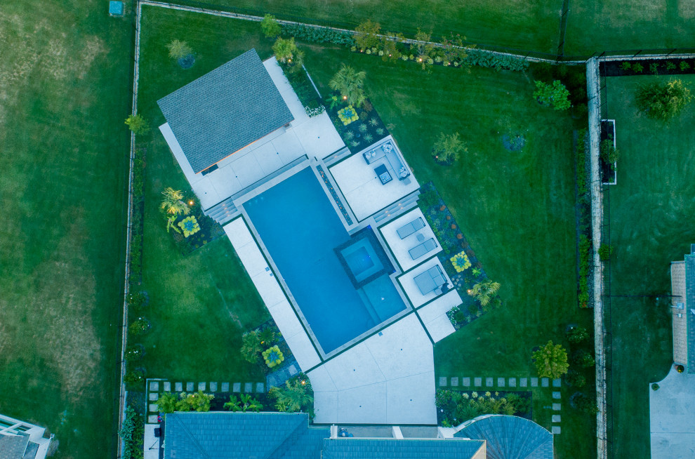 Großer Moderner Infinity-Pool hinter dem Haus in individueller Form mit Wasserspiel und Stempelbeton in Dallas