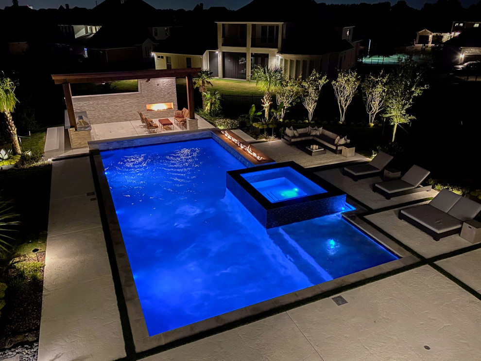 Immagine di una grande piscina a sfioro infinito minimalista personalizzata dietro casa con fontane e cemento stampato