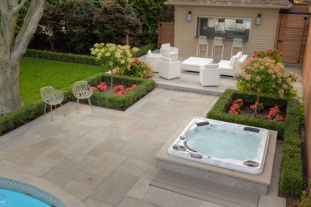 Ejemplo de piscinas y jacuzzis alargados contemporáneos grandes redondeados en patio trasero con adoquines de piedra natural