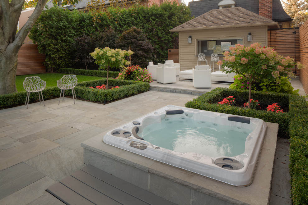 Immagine di una grande piscina monocorsia minimal rotonda dietro casa con pavimentazioni in pietra naturale e una vasca idromassaggio