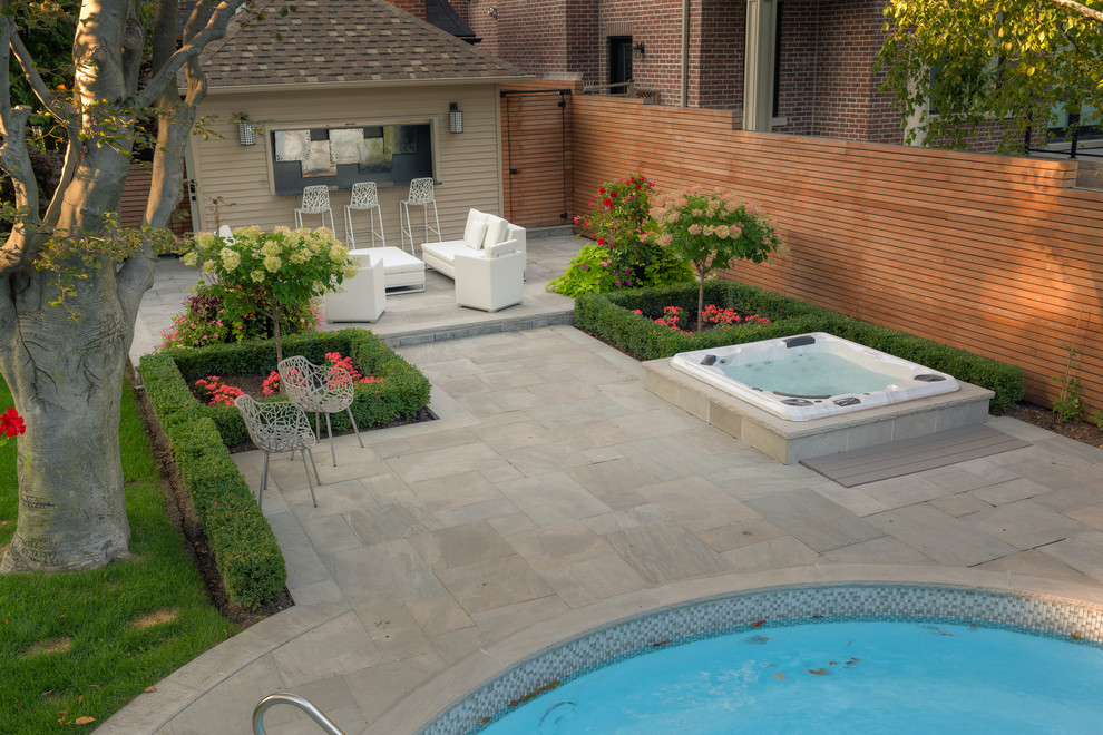 Inspiration for a large contemporary back round lengths hot tub in Toronto with natural stone paving and a shelter.