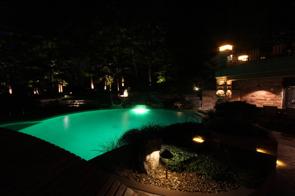 Exempel på en mycket stor modern njurformad pool längs med huset, med en fontän och naturstensplattor