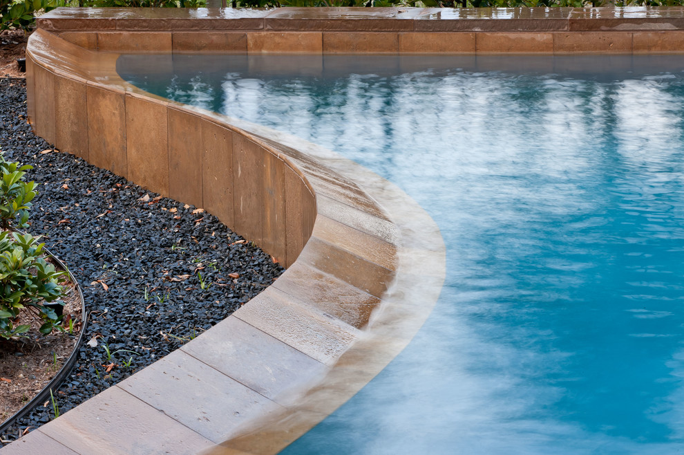Ejemplo de piscina minimalista de tamaño medio a medida en patio trasero con adoquines de piedra natural
