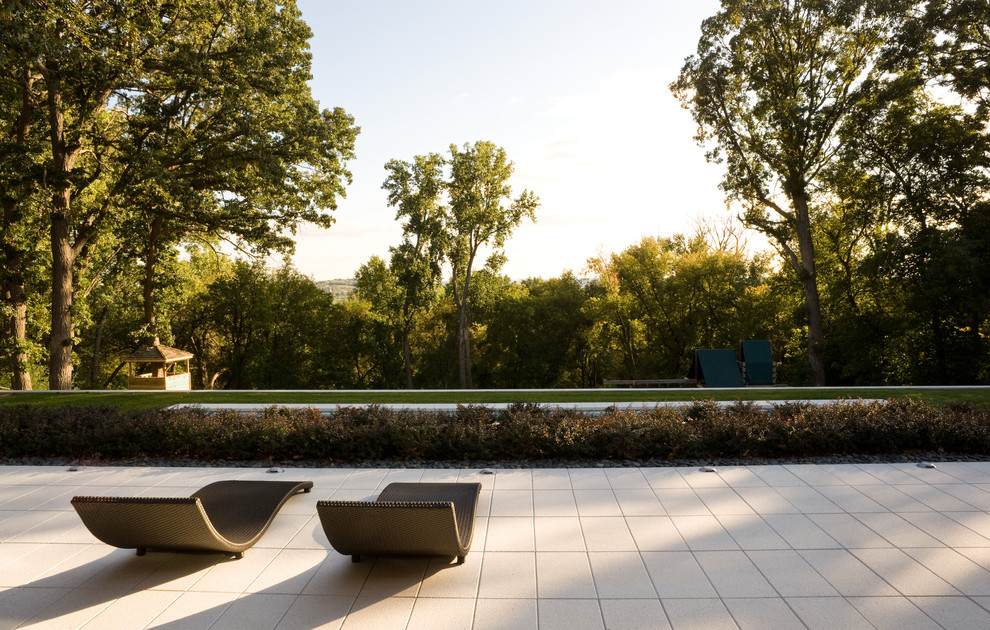 Diseño de piscina moderna de tamaño medio rectangular en patio trasero con adoquines de hormigón