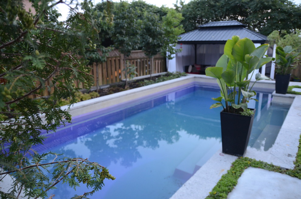 Imagen de piscina actual pequeña rectangular en patio trasero con losas de hormigón