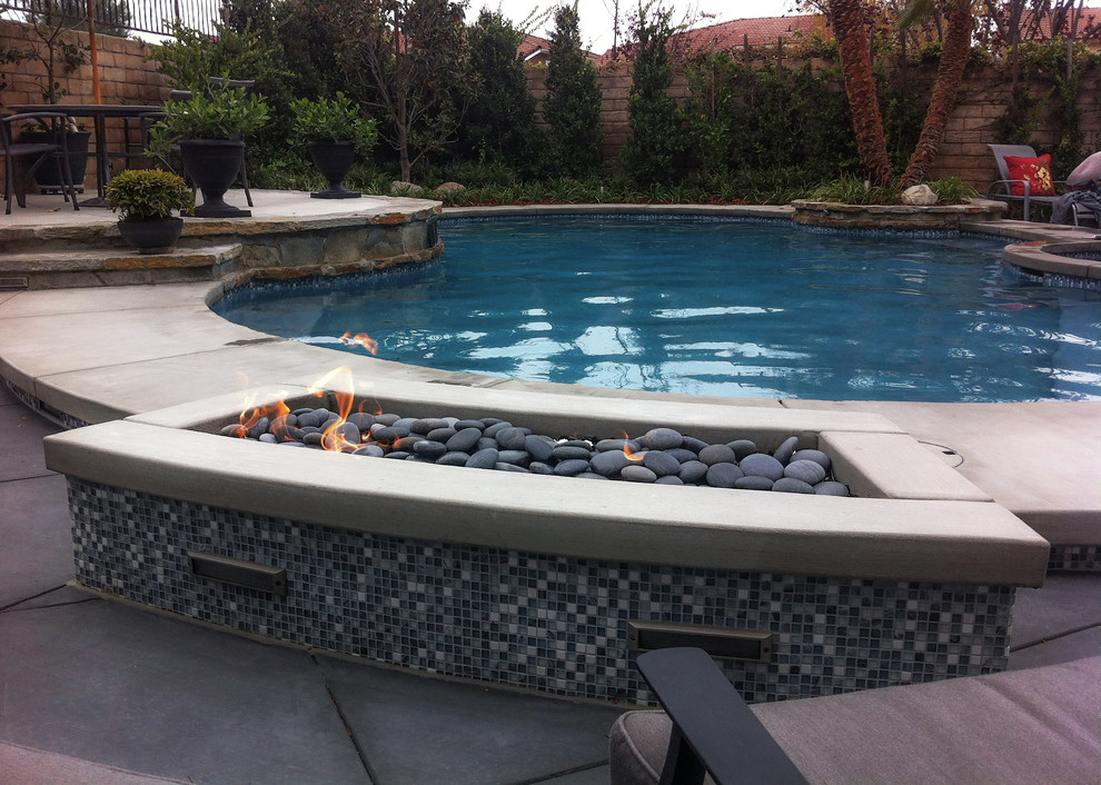 На фото: наземный бассейн среднего размера, произвольной формы на заднем дворе в стиле модернизм с джакузи и покрытием из бетонных плит с