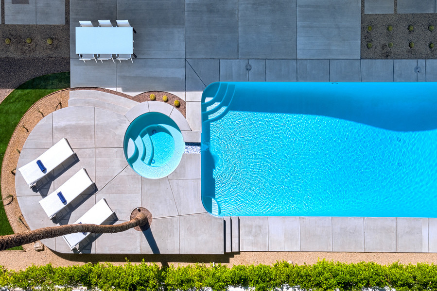 Diseño de piscina minimalista rectangular en patio trasero con losas de hormigón
