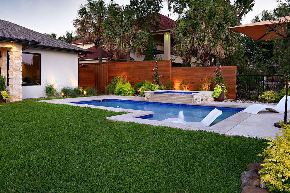 Esempio di una piscina moderna a "L" di medie dimensioni e dietro casa con una vasca idromassaggio e pavimentazioni in pietra naturale