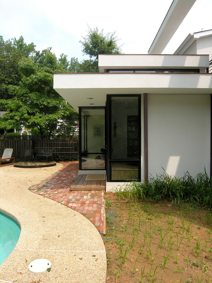 Стильный дизайн: естественный бассейн среднего размера, в форме фасоли на заднем дворе в стиле модернизм с покрытием из каменной брусчатки - последний тренд