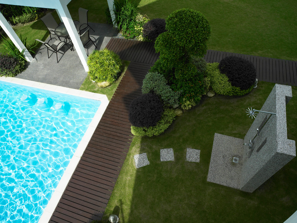 Réalisation d'un grand Abris de piscine et pool houses arrière minimaliste rectangle avec une terrasse en bois.
