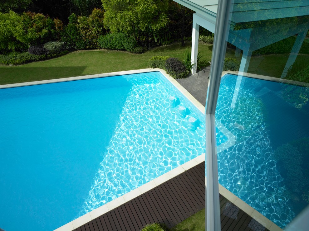 Esempio di una grande piscina naturale minimalista rettangolare dietro casa con una dépendance a bordo piscina e pedane