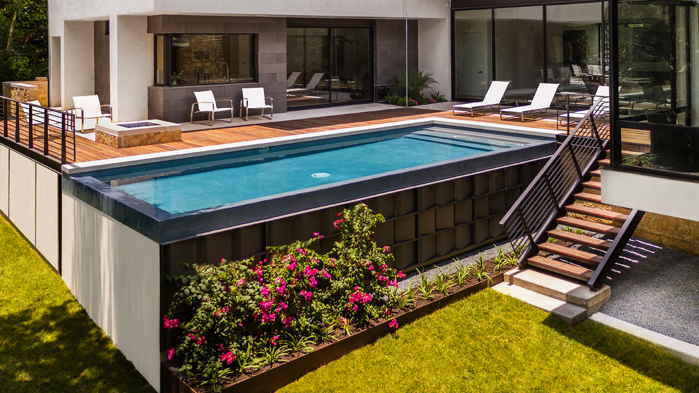 Ispirazione per una piscina a sfioro infinito moderna rettangolare di medie dimensioni e dietro casa con pedane