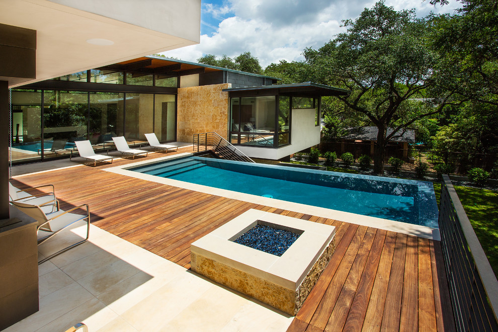 Diseño de piscina infinita moderna de tamaño medio rectangular en patio trasero con entablado