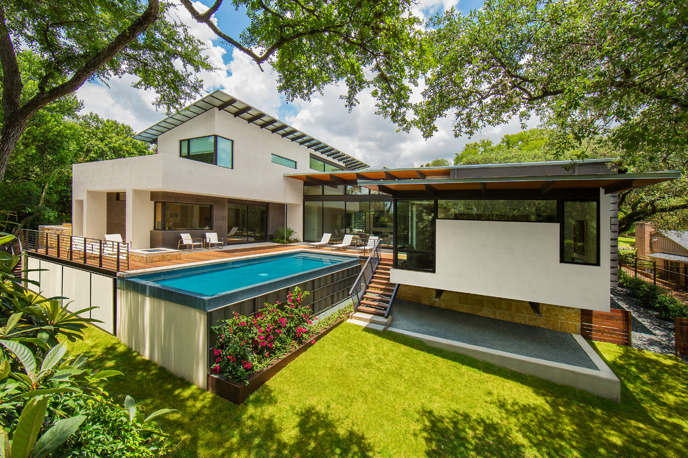 Esempio di una piscina a sfioro infinito moderna rettangolare di medie dimensioni e dietro casa con pedane