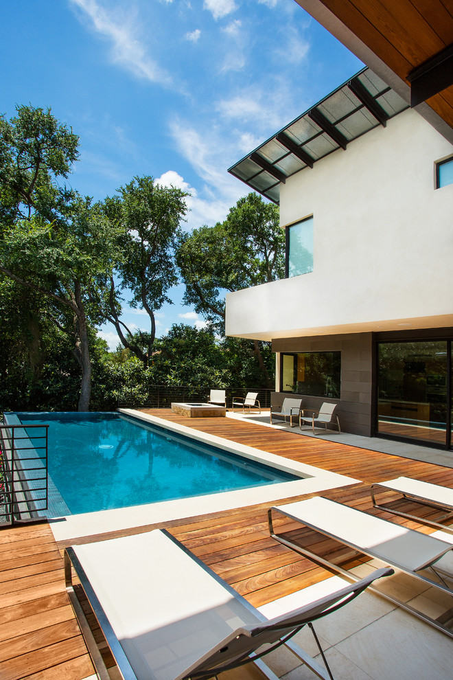 Immagine di una piscina a sfioro infinito moderna rettangolare di medie dimensioni e dietro casa con pedane