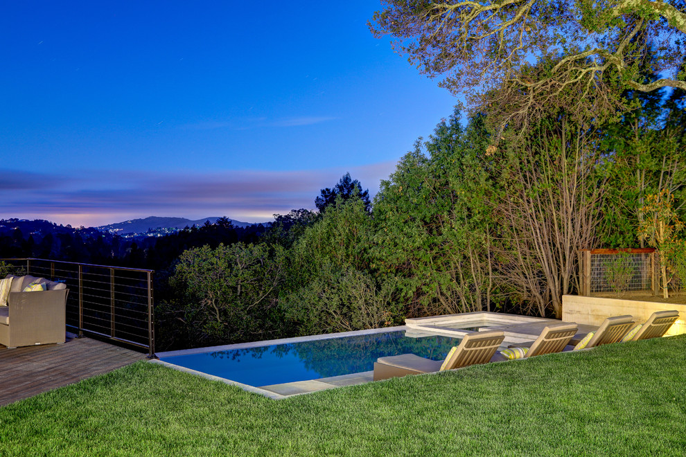 Modelo de piscina alargada contemporánea grande rectangular en patio trasero con losas de hormigón