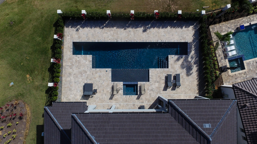 Ispirazione per una grande piscina monocorsia design personalizzata dietro casa con una vasca idromassaggio e pavimentazioni in pietra naturale