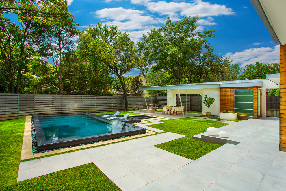 Ispirazione per una piscina a sfioro infinito design rettangolare di medie dimensioni e dietro casa con una vasca idromassaggio e pavimentazioni in cemento