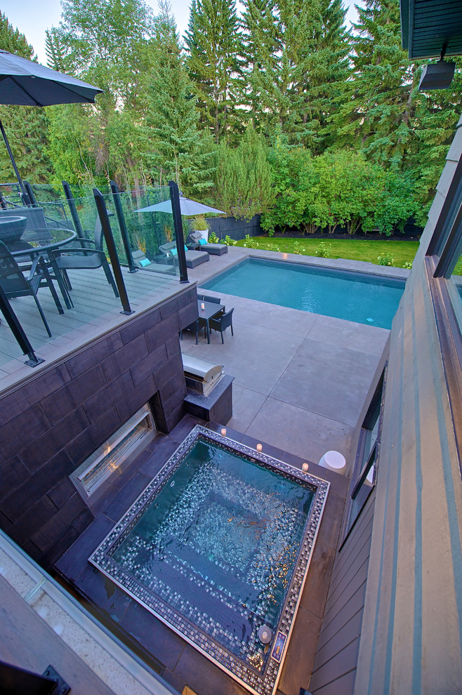 Immagine di una piscina minimalista di medie dimensioni e dietro casa con una vasca idromassaggio