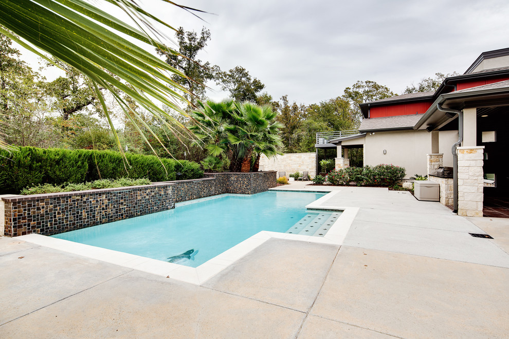 Diseño de piscina minimalista de tamaño medio rectangular en patio trasero con losas de hormigón