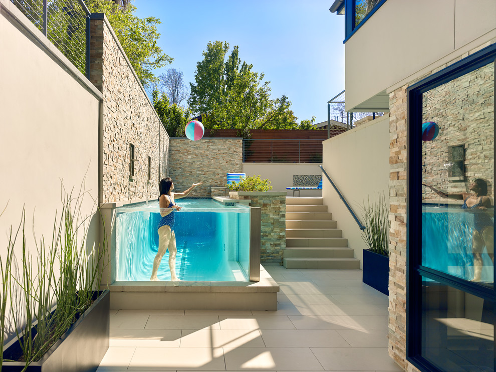 Immagine di una grande piscina monocorsia contemporanea rettangolare dietro casa con fontane e piastrelle