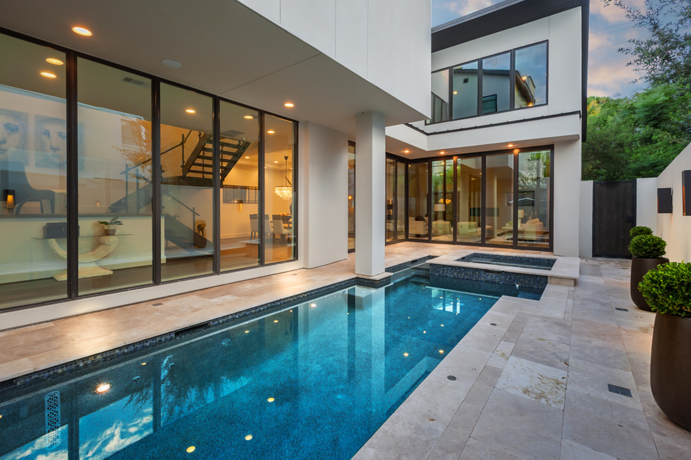 Esempio di una piscina monocorsia chic rettangolare di medie dimensioni e nel cortile laterale con una vasca idromassaggio e pavimentazioni in pietra naturale