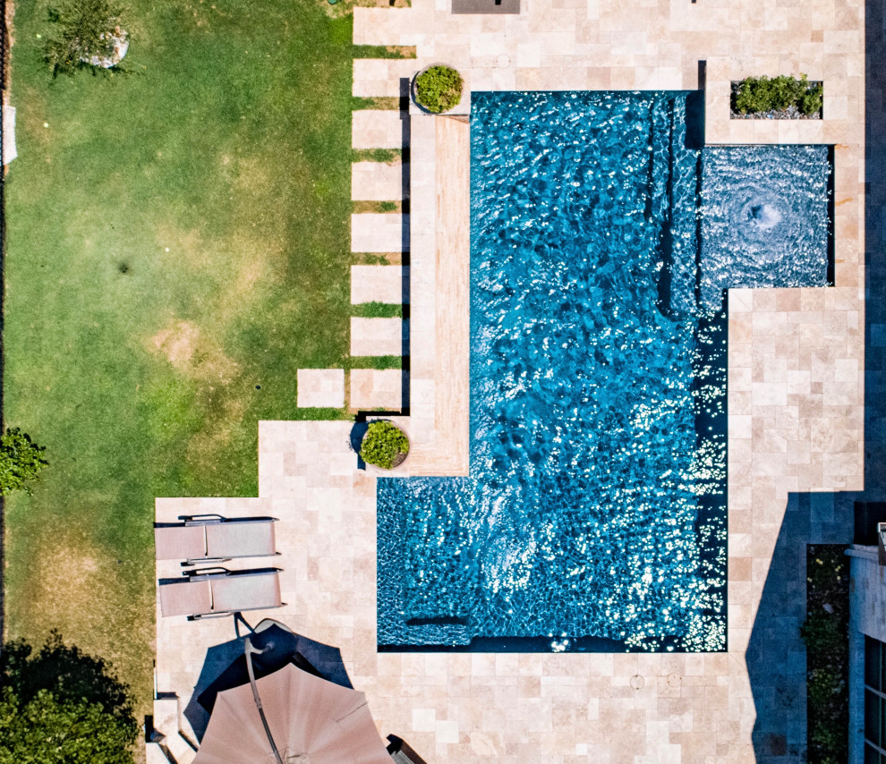 Diseño de piscina con fuente clásica renovada de tamaño medio rectangular en patio trasero con adoquines de piedra natural
