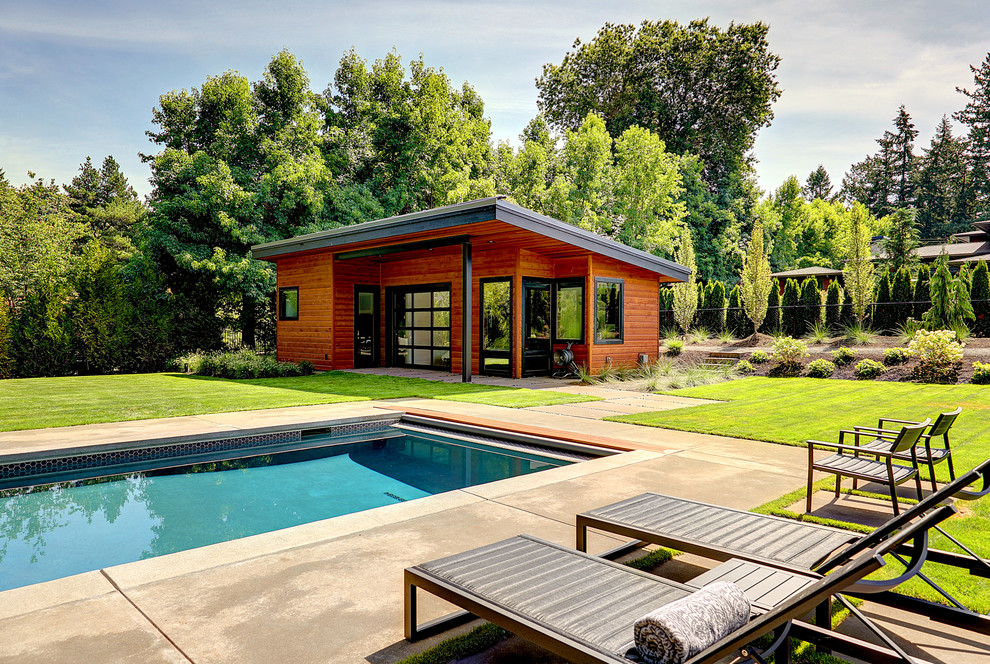 Imagen de casa de la piscina y piscina alargada actual grande rectangular en patio trasero con adoquines de hormigón