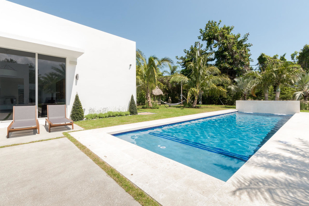 Ejemplo de piscina alargada moderna de tamaño medio rectangular en patio trasero con losas de hormigón