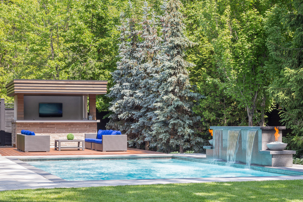 Imagen de piscina con fuente alargada contemporánea de tamaño medio rectangular en patio trasero con entablado