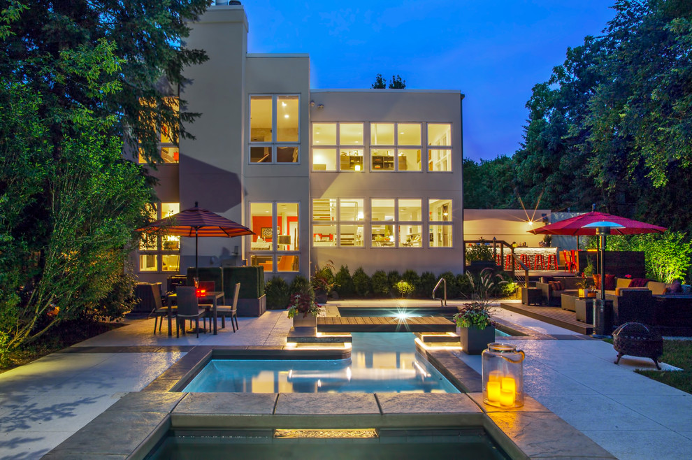 Modelo de piscina con fuente infinita contemporánea grande rectangular en patio trasero con losas de hormigón