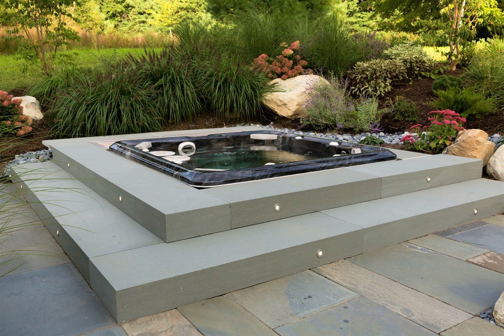 Réalisation d'une piscine hors-sol et arrière minimaliste rectangle avec un bain bouillonnant et des pavés en pierre naturelle.