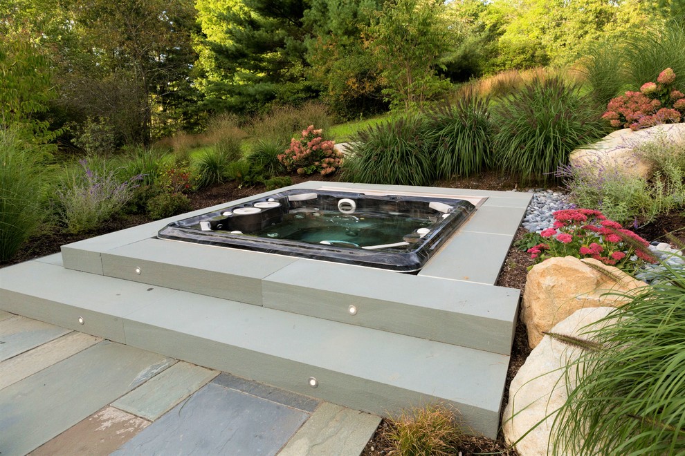Ispirazione per una piscina fuori terra minimalista rettangolare dietro casa con una vasca idromassaggio e pavimentazioni in pietra naturale
