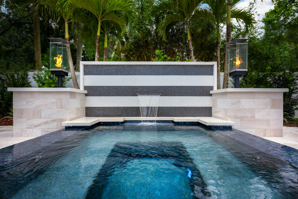 Ispirazione per una piscina a sfioro infinito design personalizzata di medie dimensioni e dietro casa con paesaggistica bordo piscina e piastrelle